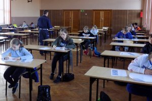 Zdjęcie uczniów siedzących przy stolikach i piszących test.