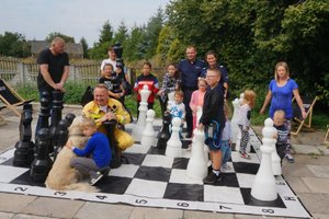 Grupowe zdjęcie - policjanci, druh OSP Niegowonice i dzieci z opiekunami na szachownicy