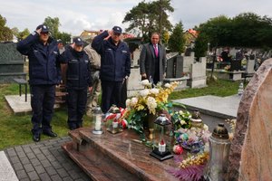 Policjanci salutują przed grobem  sierżanta Grzegorza Załogi