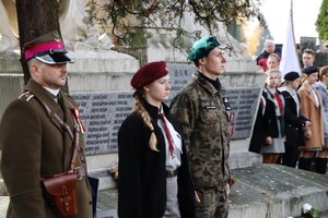 Umundurowany żołnierz i harcerze na tle Pomnika Niepodległości.