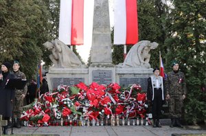 Zdjęcie Pomnika Niepodległości i złożonych przed nim wiązanek kwiatów.