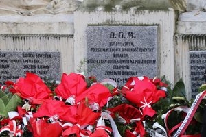 Zdjęcie jednej z tablic Pomnika Niepodległości. Pod spodem wiązanki kwiatów.