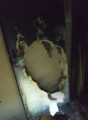 Drzwi wejściowe do mieszkania, w którym wybuchł pożar z wybitym otworem, dzięki któremu policjanci dostali się do środka lokalu.