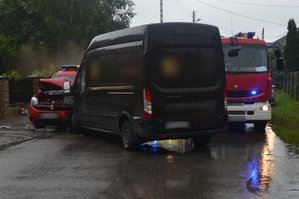 Widoczne dwa samochody, które się zderzyły brązowy cięzarowy i czerwony straży pożarnej. Widoczny także wóz strażacki.