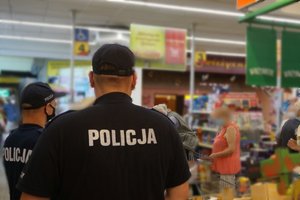 Widoczni na terenie dyskontu policjanci podczas sprawdzenia czy klienci sklepu noszą maaseczki ochronne.