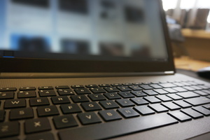 Na zdjęciu widoczna klawiatura laptopa, w tle ekran.