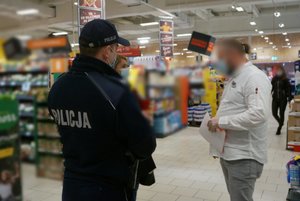 Umundurowany policjant wraz z przedstawicielką Powiatowej Stacji Sanitarno - Epidemiologicznej w Zawierciu rozmawiają z pracownikiem sklepu