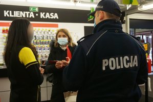 Umundurowany policjant wraz z przedstawicielką Powiatowej Stacji Sanitarno - Epidemiologicznej w Zawierciu rozmawiają z pracownikiem sklepu