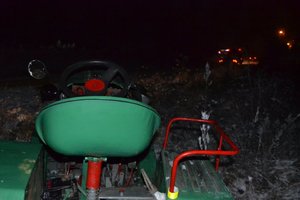 Na zdjęciu widoczne siedzisko ciągnika. W tle światła pojazdów służb ratunkowych.