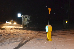 Widoczne miejsce zdarzenia - po lewej stronie radiowóz stojący obok wiaty przystanku autobusowego. Na środku widoczne drogowe oznakowania pionowe.