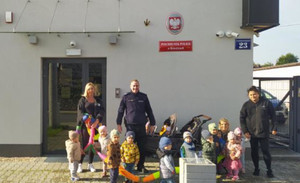 Zdjęcie grupowe przed Posterunkiem Policji w Kroczycach, na którym widać dzieci wraz z opiekunkami oraz dzielnicowym.