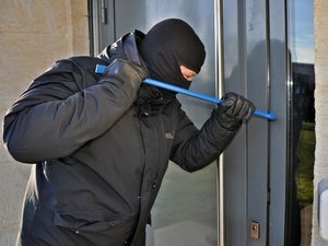 Na zdjęciu widoczny mężczyzna w kominiarce, który łomem próbuje otworzyć drzwi. Zdjęcie: Komenda Powiatowa Policji w Zakopanem.