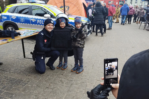 Na zdjęciu widoczny policjant oraz dwóch chłopców w policyjnym sprzęcie, którzy pozują do zdjęcia.