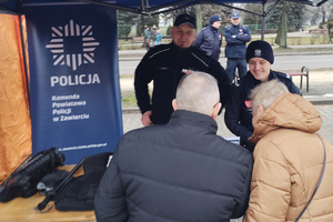 Na zdjęciu widoczne starsze osoby przy policyjnym stoisku.
