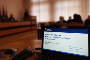 Na zdjęciu widoczny ekran laptopa, na którym wyświetlony jest slajd tytułowy prezentacji: Odprawa roczna Komendy Powiatowej Policji w Zawierciu.